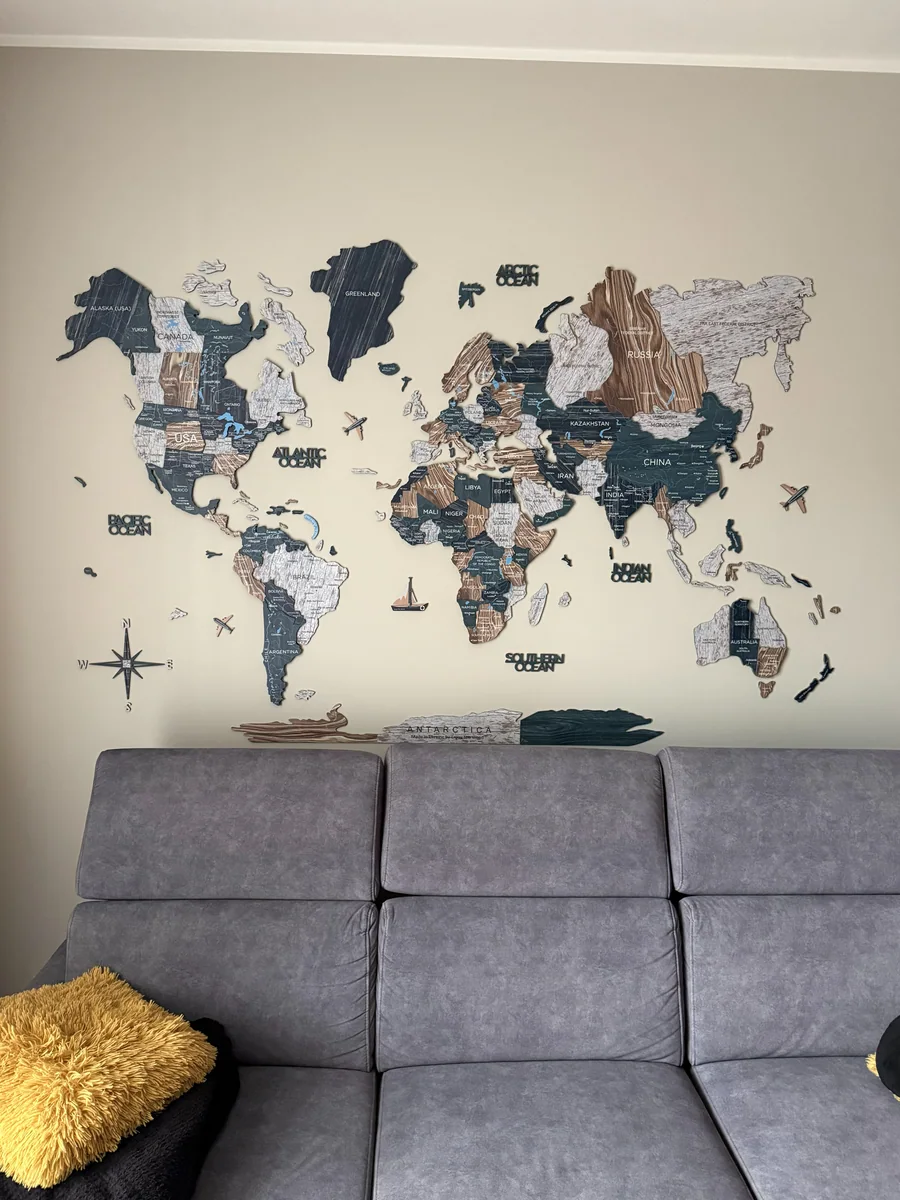 Room-scale photo of an Enjoy The Wood map installed above a sofa