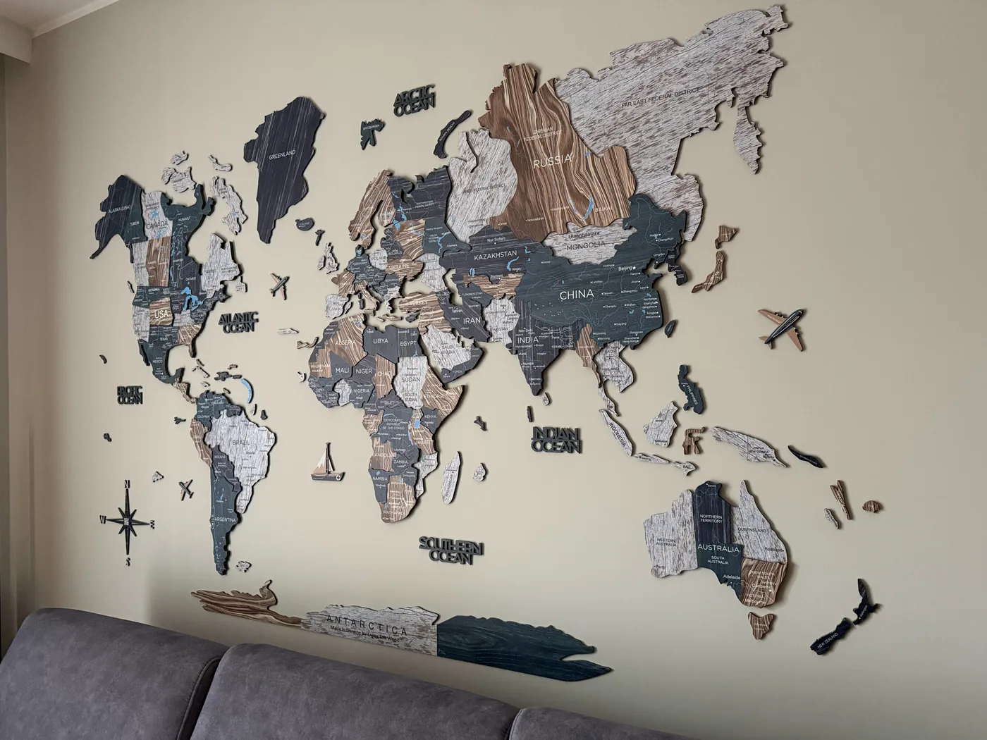 Original photo of an Enjoy The Wood wooden world map mounted above a sofa
